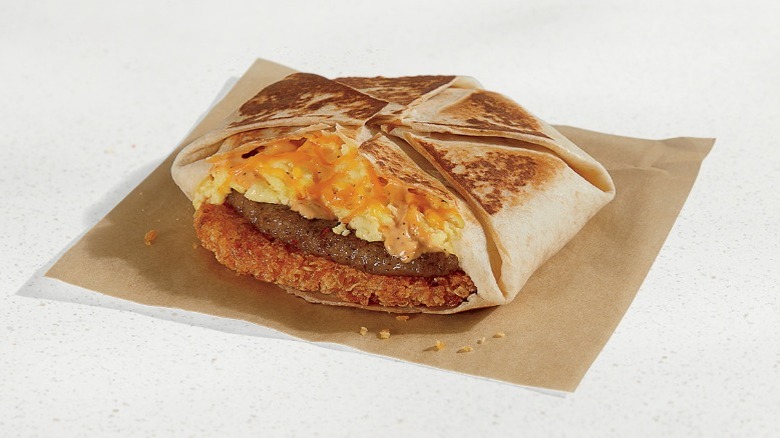 Taco Bell Breakfast Crunchwrap with a hashbrown, sausage, eggs, and cheese on a brown napkin
