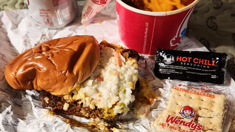 Carolina Classic from Wendy's, sitting on wrapper with a cup of chili, crackers, and sauce packet