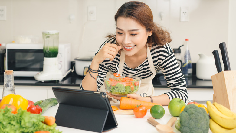 Person in apron watching tablet with salad