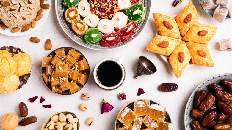 Assortment of baklava, lokum, pistachios, almonds, dates, halva, and coffee