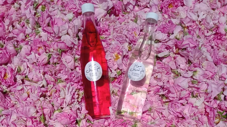 Glass bottles of rose water and rose syrup on a bed of rose petals