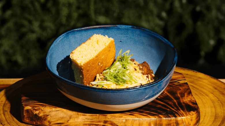 Vegetarian chili in a blue bowl with cheese with green onions and cornbread