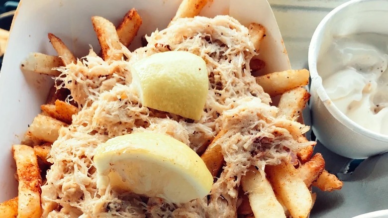 Fries with Dungeness crab and lemon wedges on top