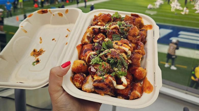 person holding Korean fried chicken loaded tots