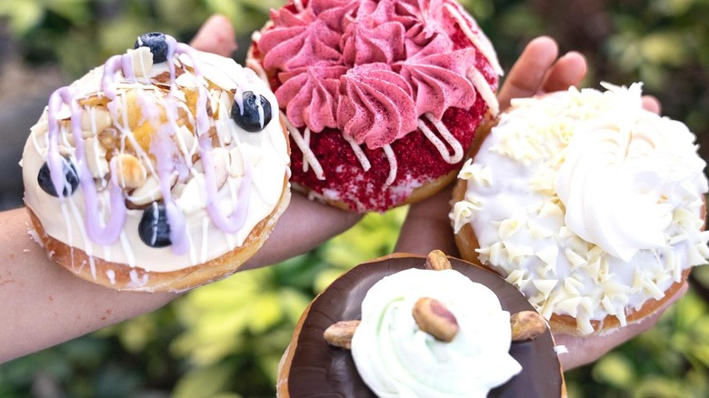 person holding four decadent donuts