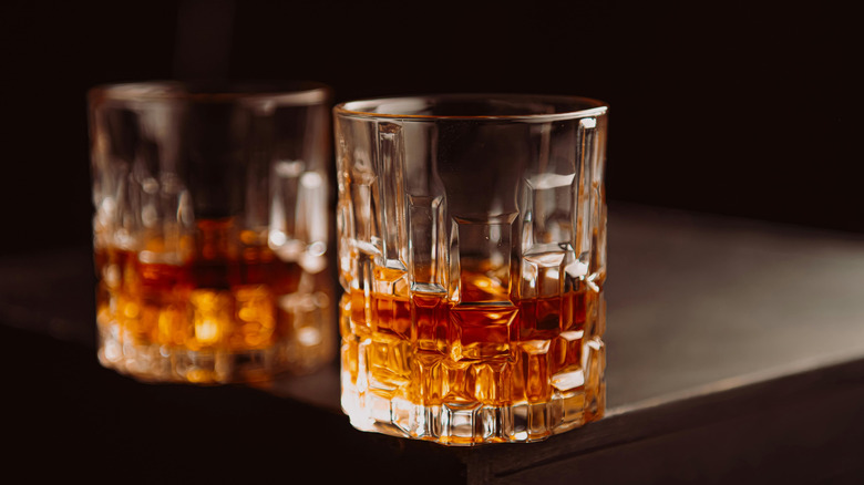Two crystal glasses of bourbon on the corner of a table