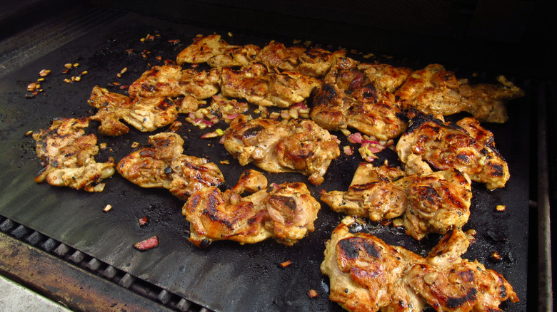 Chicken thighs cooking on a barbecue grill