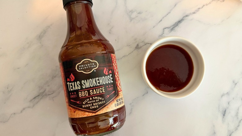 Bottle and bowl of Private Selection Texas Smokehouse BBQ Sauce on white marbled surface