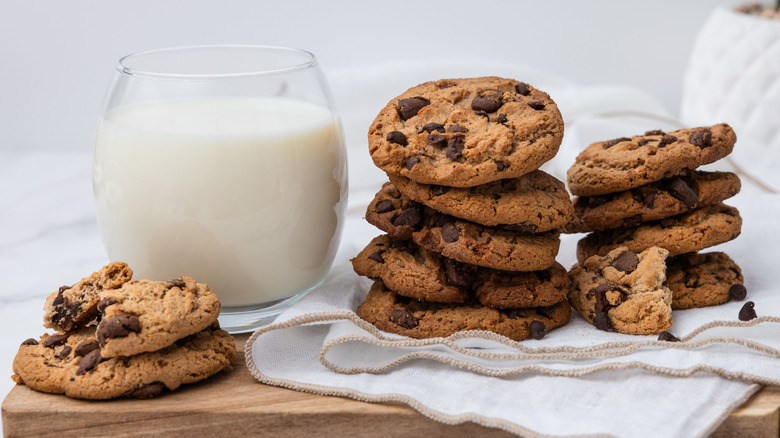 three piles of chocolate chip cookies next to a glass of milk