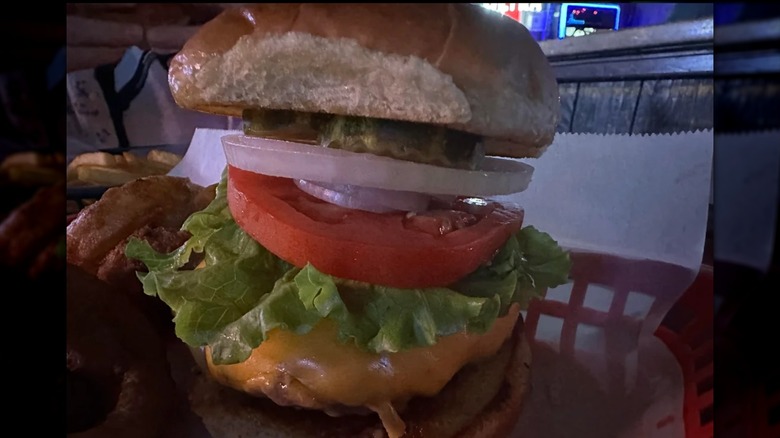 Burger with lettuce, onion, tomato, pickles, and cheese