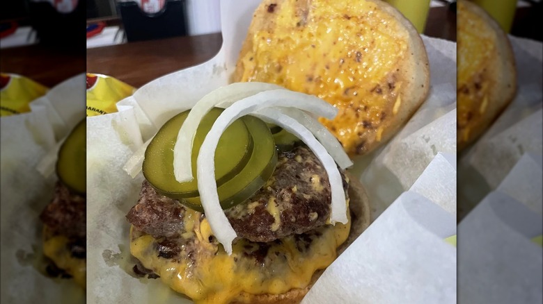 Open burger with cheese, pickles, and onions