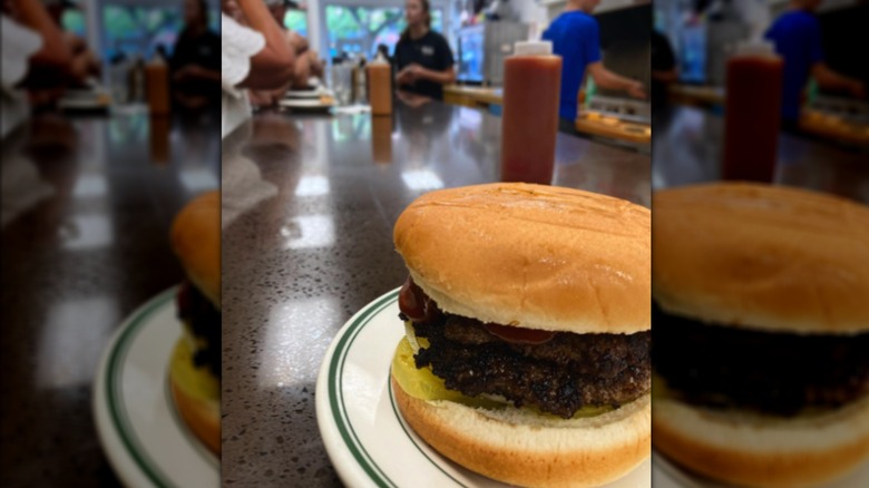 Burger on a plate on a counter with people in the background
