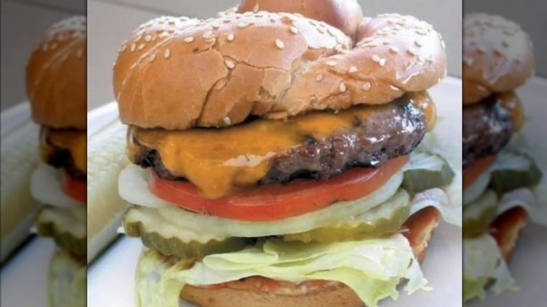 Burger with cheese, lettuce, onions, tomato, and pickles