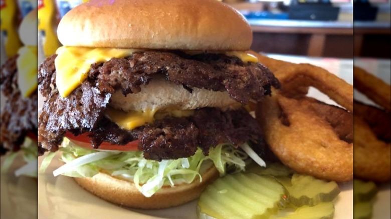 Double smashburger with lettuce, tomato, cheese, and pickles on the side