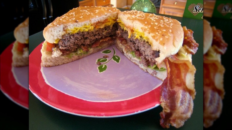 Burger on a plate cut in half with lots of bacon