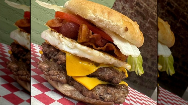 Double cheeseburger with bacon and lettuce on red and white paper