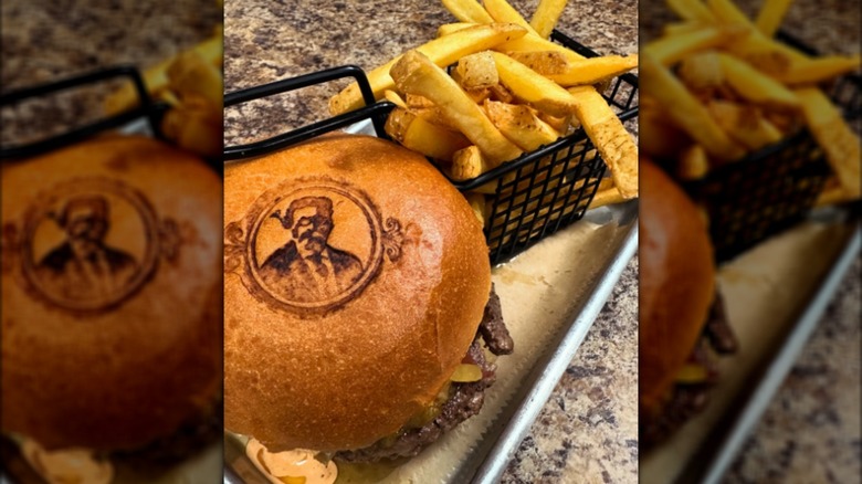 Burger with Teddy Roosevelt brand in the bun and black wire basket of fries