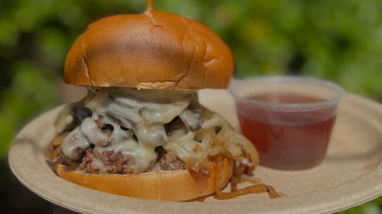 French dip burger with onions and cheese on plate with dip