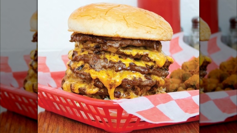 Burger with multiple patties and cheese on red plastic tray with paper