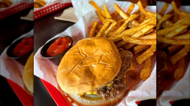 Burger and side of ketchip with fries in red plastic tray