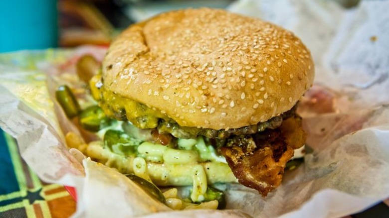 Burger with bacon and mac and cheese on paper