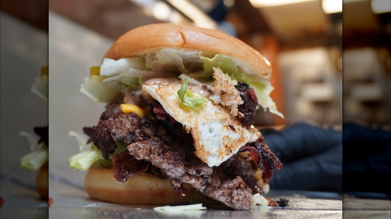 Tall burger with fried egg and blurred background