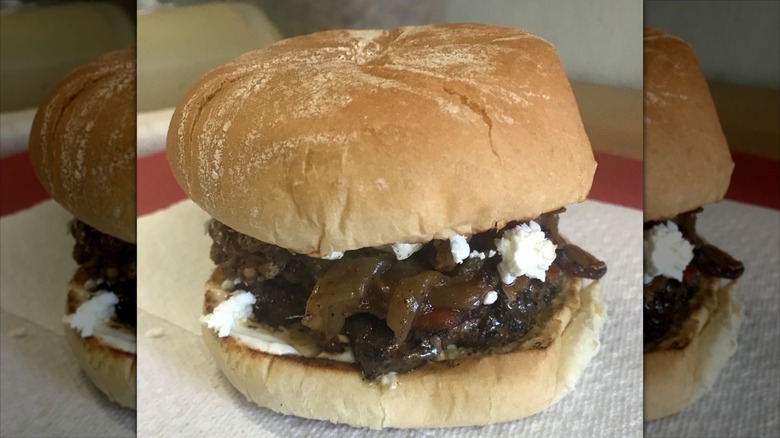 Burger with onions and cheese on paper towel