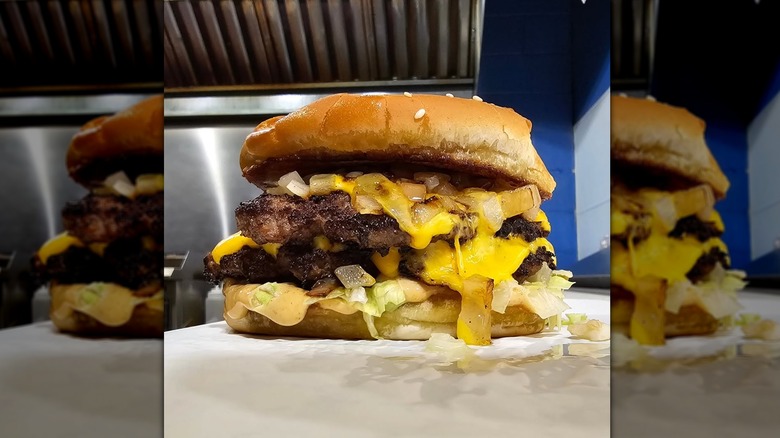 A tall burger with sauce and lettuce