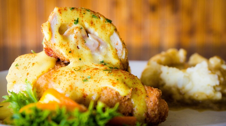 Deep friedn chicken cordon bleu halved with hollandaise sauce