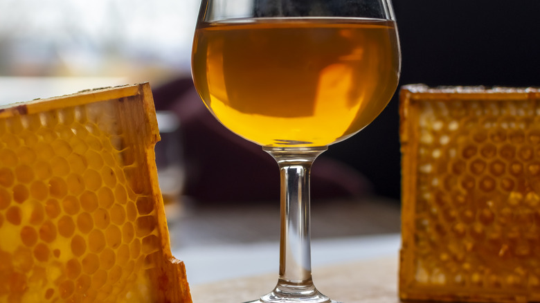 A glass of whiskey sits beside two honeycombs