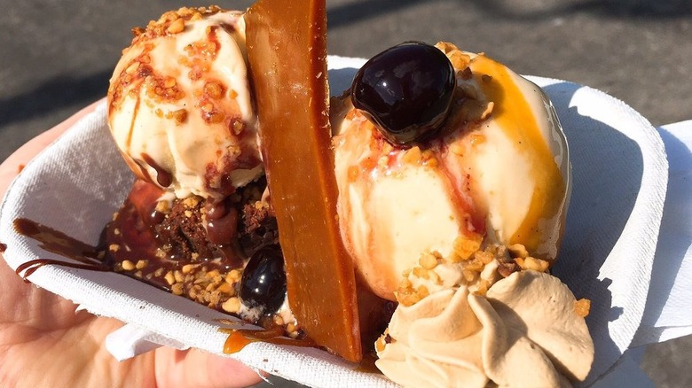Ice cream sundae featuring brownie, hazelnut vanilla ice cream, toffee brittle, fudge, whipped cream, salted caramel, and cherries