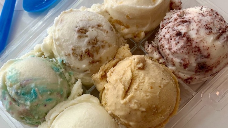 Flight of six different ice cream flavors in plastic container with spoons