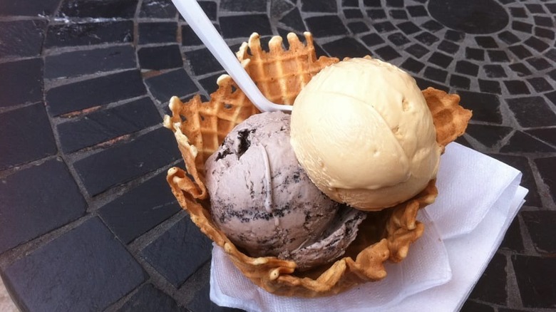 Cookies n cream and salted caramel ice cream scoops in waffle bowl on table