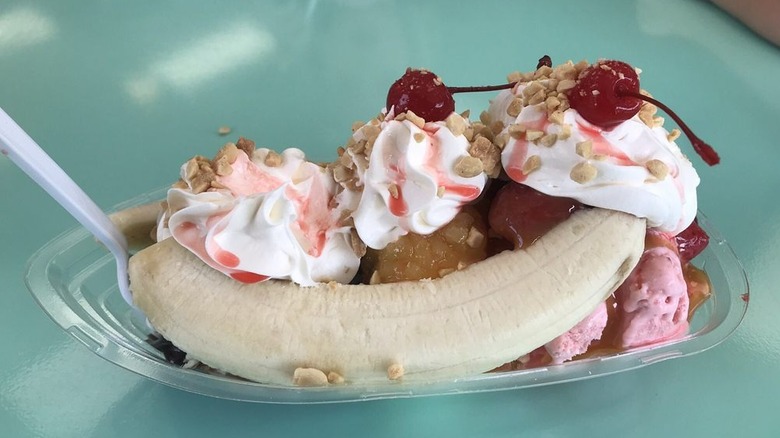 Banana split topped with whipped cream, nuts, and two cherries