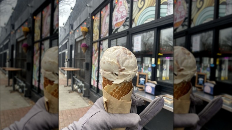 Gloved hand holding cone with scoop of ice cream in front of High Hopes storefront