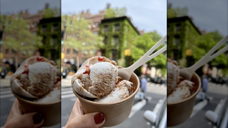 Hand holding cup filled with ice cream on New York City street