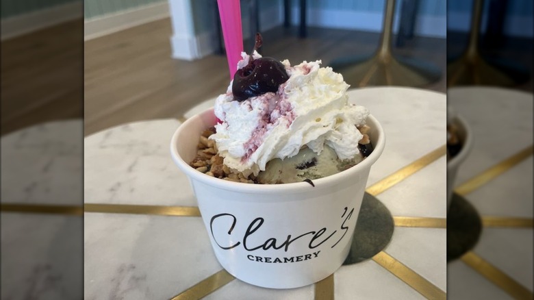 Hot fudge sundae in cup topped with whipped cream and cherry