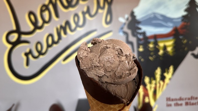 Ice cream in chocolate dipped waffle cone with mural in background