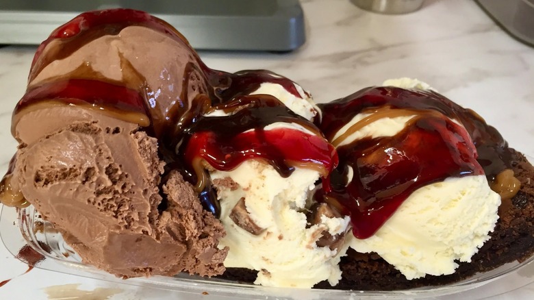 Brownie and three scoops of ice cream topped with syrup