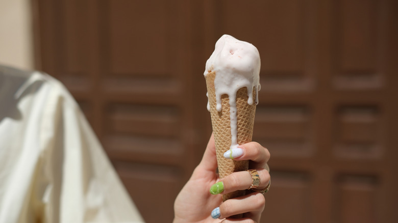 Hand holding melting ice cream cone