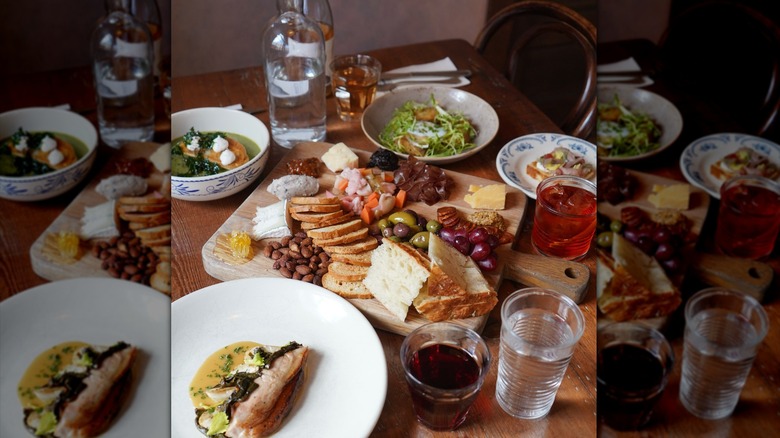 A table with a charcuterie board, a bowl of salad, and plates with sandwiches