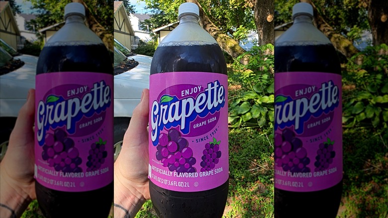 Hand holding a two-liter bottle of Grapette soda