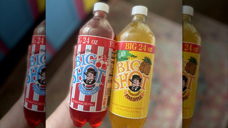Hand holding a bottle of Big Shot Red Creme and a bottle of Big Shot Pineapple