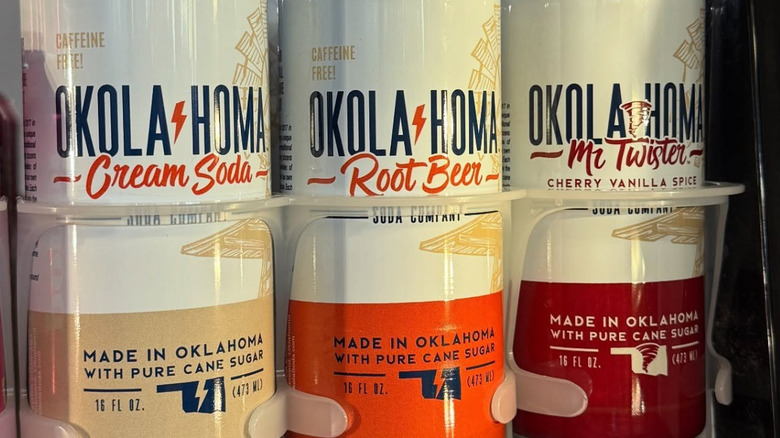 Three cans of Okola-homa Soda Co.: cream soda, root beer, and cherry vanilla spice