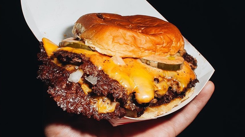 Hand holding smash burger from Love Hour