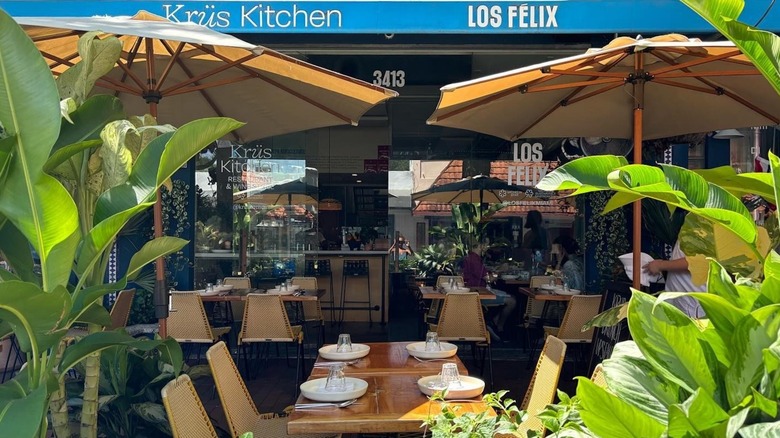 The dining room at Los Félix featuring a colorful mural, woven lampshades and empty wooden tables