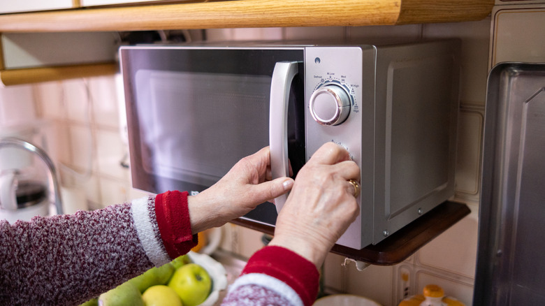 A woman adjusting a setting on a microwave