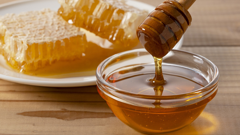 Dish of pure organic honey beside whole honeycomb