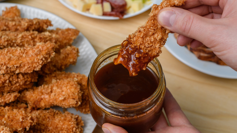 Foodie dunking panko-breaded wings into a dish of barbecue sauce