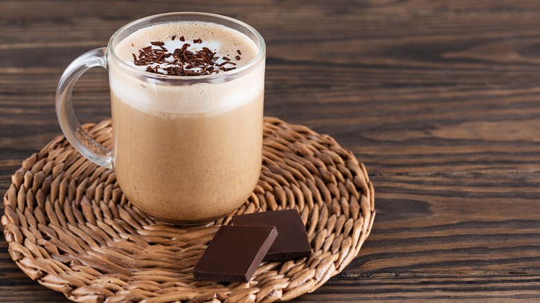 Mocha in glass mug with two pieces of dark chocolate